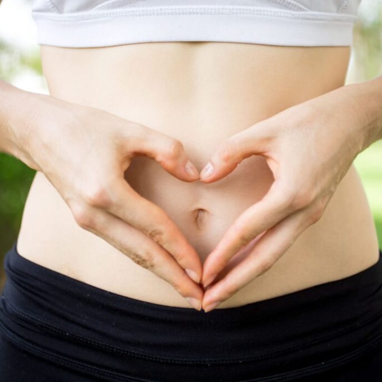 Salud digestiva: intolerancias alimentarias y SIBO Primer plano: manos femeninas moldeando el vientre del corazón